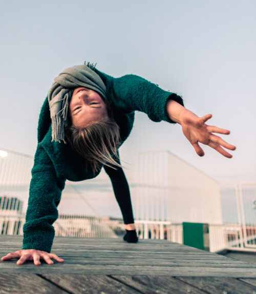 Camilla practicing yoga on a rooftop at sunrise. She's doing a wild thing and working on fulfillment in her yoga practice