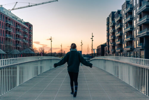 Camilla walking into the sunrise on a bridge. She's working on fulfillment in her yoga practice