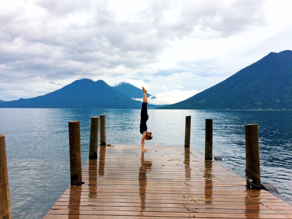 Complete handstand guide picture of Camilla handstanding on a bridge overlooking the volcanoes surrounded Late Atitlan in Guatemala