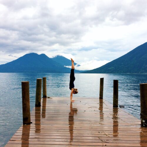 Complete handstand guide picture of Camilla handstanding on a bridge overlooking the volcanoes surrounded Late Atitlan in Guatemala