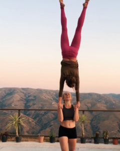 Standing acrobatics / acroyoga where Camilla is lady basing Emily in a hand-to-hand