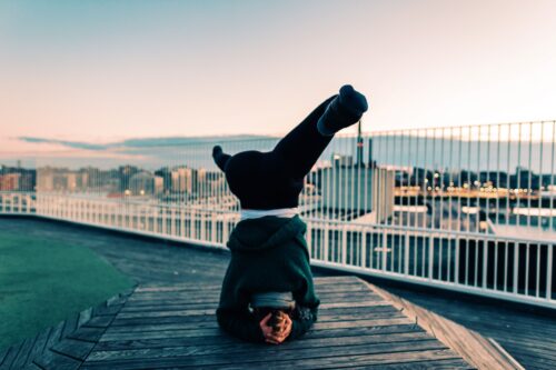 Camilla practicing yoga on a rooftop at sunrise. She's doing a headstand and working on empowerment in her yoga practice